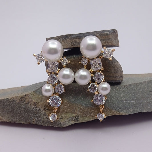 Pair of pearl earrings on a stone surface with a white background